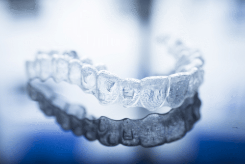 An Invisalign aligern on a blueish background